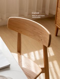 a laptop computer sitting on top of a wooden desk next to a chair and table