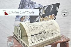 an open book sitting on top of a wooden bench next to a christmas card display