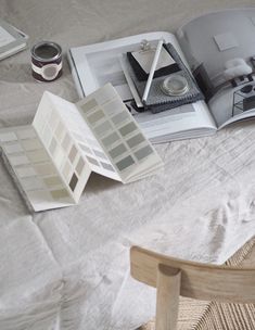 an open book sitting on top of a bed next to a wooden chair and table