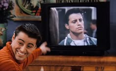 a young man is smiling in front of a television with the image of him on it