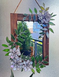 a wooden frame with flowers hanging from it's side and a mirror in the background