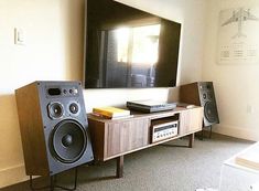 an entertainment center with speakers and a large television mounted on the wall in front of it