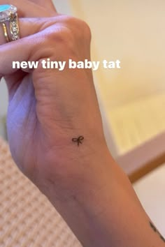 a small tattoo on the wrist of a woman's left hand that reads, new tiny baby tat