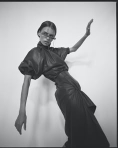 a black and white photo of a woman in a leather dress with her arms stretched out