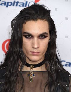 a woman with long black hair wearing a choker and cross necklace on her neck