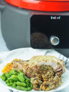 a white plate topped with meat and green beans next to an instant pot roaster