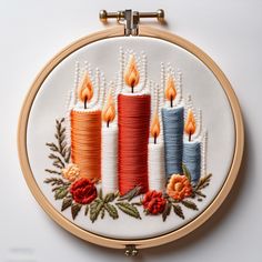 a close up of a embroidery on a white surface with candles and flowers in it