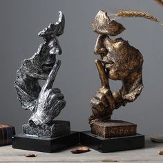 two sculptures made out of metal are sitting on top of each other and one is holding a feather