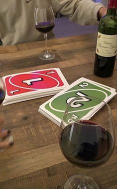 two people are sitting at a table with wine glasses and signs on the wooden table