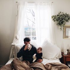 a man sitting on top of a bed holding a baby