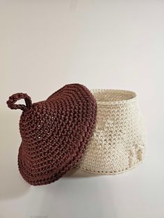 two crocheted baskets sitting next to each other on a white surface with one bag in the middle