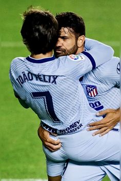 two soccer players hugging each other on the field