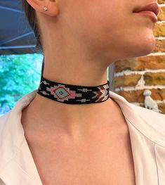 A black beaded choker with a geometric pattern, featuring vibrant elements in turquoise, pink, white, and brown tones. The piece is adorned with silver-colored metal elements and an adjustable chain, allowing you to customize the size to your preference. An excellent choice for creating a stylish and original look. Made of Czech beads. Hypoallergenic clasp. Length 12.8 inches (32.7 cm)+Chain extension 2 inches (5cm). Taking the clasp into account. Width 1.1 inches (2.9 cm). If you want this chok Black Southwestern Necklaces For Festivals, Black Southwestern Necklace For Festival, Southwestern Style Black Necklace For Festival, Southwestern Style Black Necklace For Festivals, Southwestern Black Beaded Necklaces For Festivals, Southwestern Black Beaded Necklace For Festivals, Adjustable Black Choker With Colorful Beads, Bohemian Black Round Beads Choker, Festival Black Beads Choker