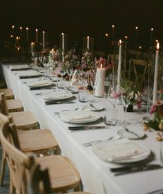 a long table is set with place settings and candles