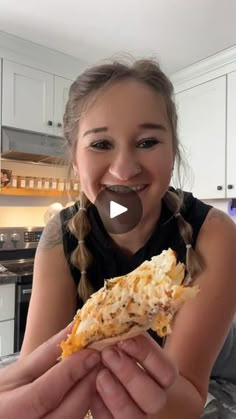 a girl is smiling and holding a piece of pizza