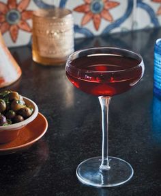 a glass of wine sitting on top of a table next to a bowl of food