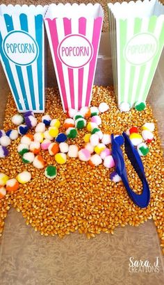 three popcorn bags filled with candy corn and one has a pair of blue handled scissors