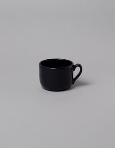 a black coffee cup sitting on top of a table