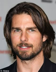 a man with long hair and beard wearing a black shirt is looking at the camera