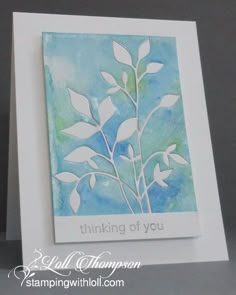 a handmade birthday card with white paper flowers and leaves on blue background, says happy birthday