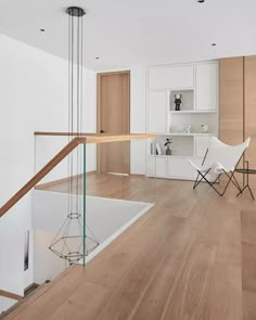 an empty living room with wooden floors and white walls, along with glass railings