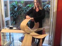 a woman is holding a large piece of wood in front of a glass case that has been made out of plywood