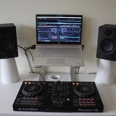 a laptop computer sitting on top of a dj's desk next to two speakers