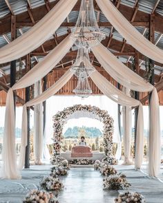 an outdoor ceremony with white draping and flowers on the floor, chandelier hanging from the ceiling