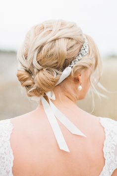 the back of a woman's head wearing a white ribbon and pearl hair comb