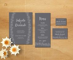 the wedding stationery is set up on top of a wooden table with flowers and place cards