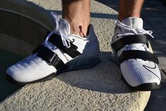 the feet of a person wearing white and black shoes with two straps on each shoe