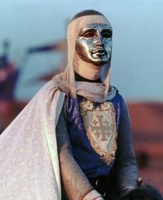 a woman with silver face paint on top of her head riding a horse in the desert