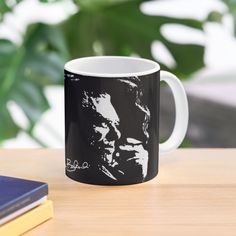 a black and white coffee mug sitting on top of a table next to a book