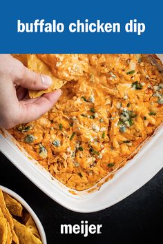 a person dipping tortilla chips into a casserole dish with buffalo chicken dip