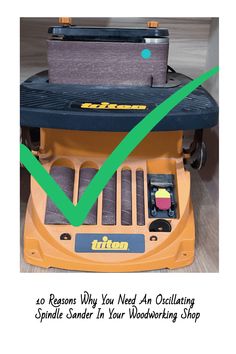 a yellow lawn mower sitting on top of a wooden floor next to a green tick mark