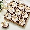 a box filled with lots of chocolates next to flowers and greenery on a white surface