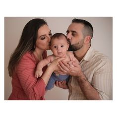 a man and woman holding a baby in their arms