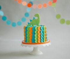 a colorful cake with a dinosaur decoration on top