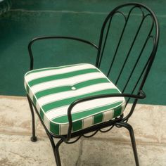 a green and white striped chair next to a pool