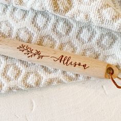 a personalized wooden baseball bat laying on top of a white and tan blanket with the name willow written on it