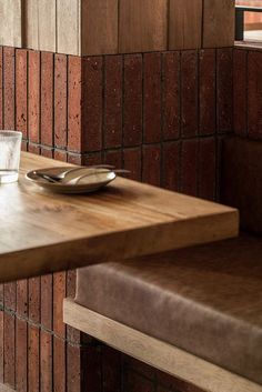 a wooden table with a plate and glass on it next to a window in a building