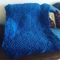 a blue blanket sitting on top of a bed next to pillows and a pillow case