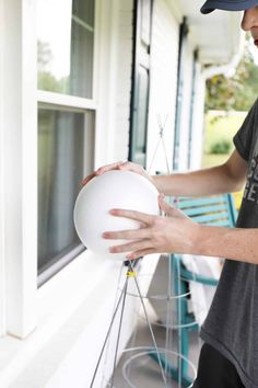 a man holding a white frisbee in front of a window on a porch