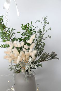 a vase filled with white flowers and greenery