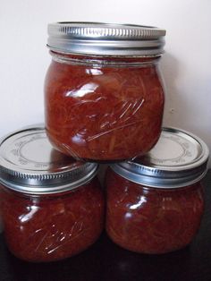 four jars filled with jam sitting on top of a table