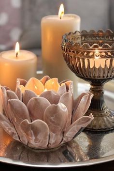 two candles are sitting on a silver tray