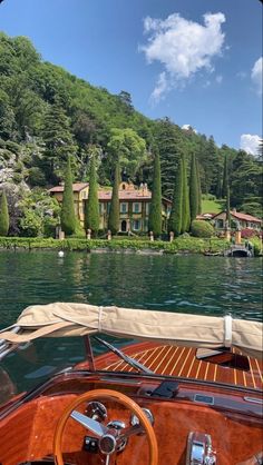 the steering wheel and dashboard of a sailboat in front of a house on a lake