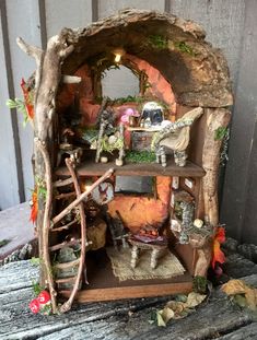 a doll house made out of wood with animals and plants on the shelves in front of it