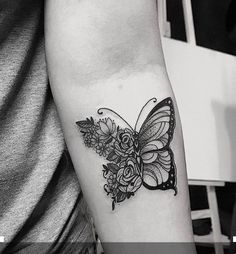 a black and white photo of a butterfly with flowers on it's back arm