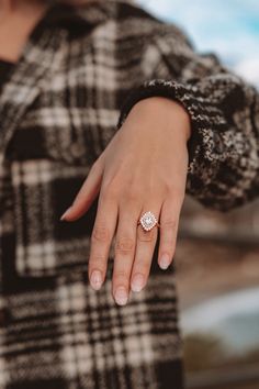 a woman's hand with a diamond ring on her left hand, wearing a black and white checkered coat